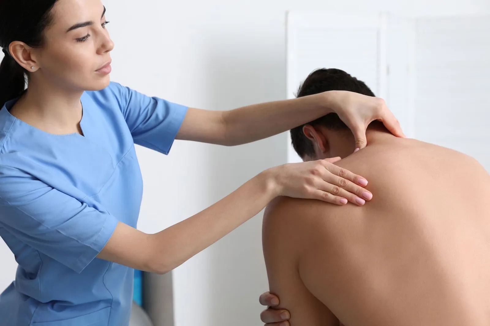 Kék ruhás terapeuta egy ülő páciens nyakát és vállát kezeli (illusztráció)