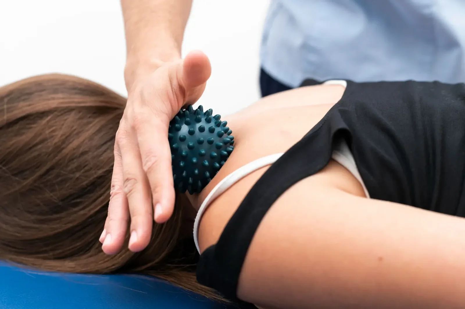 Tüskés masszázslabda a lapocka környékén, a terapeuta kezében (illusztráció)